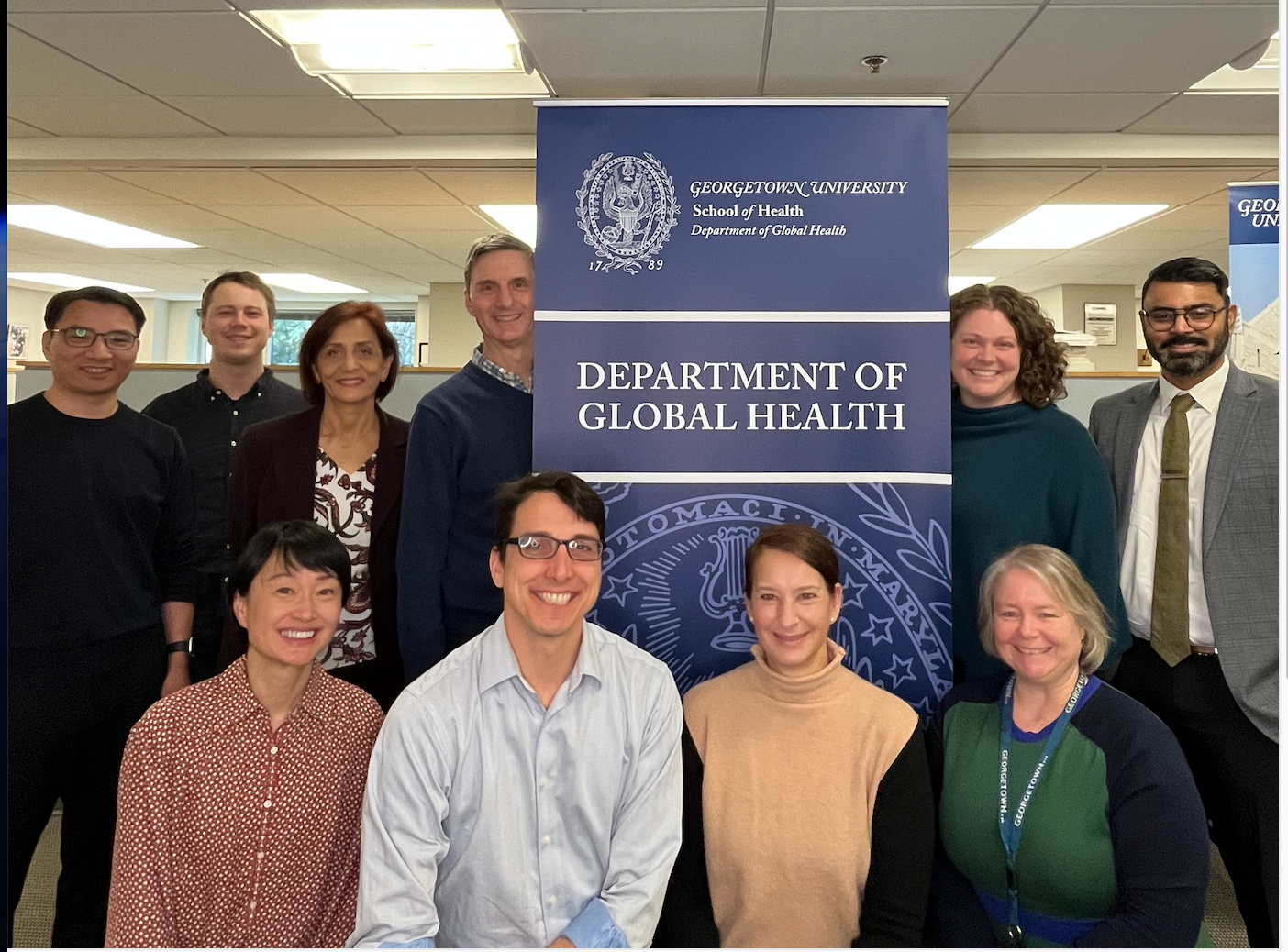 Dept. of Global Health faculty and staff gathered at dept. banner